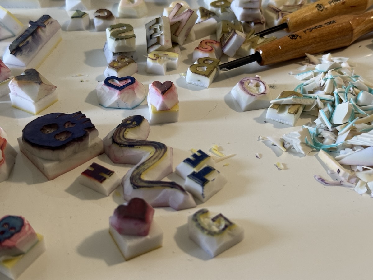 Hand-carved rubber stamps scattered beside carving tools.