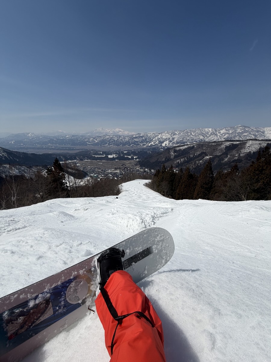 A snowboard resting on a snowy slope above a mountain valley.